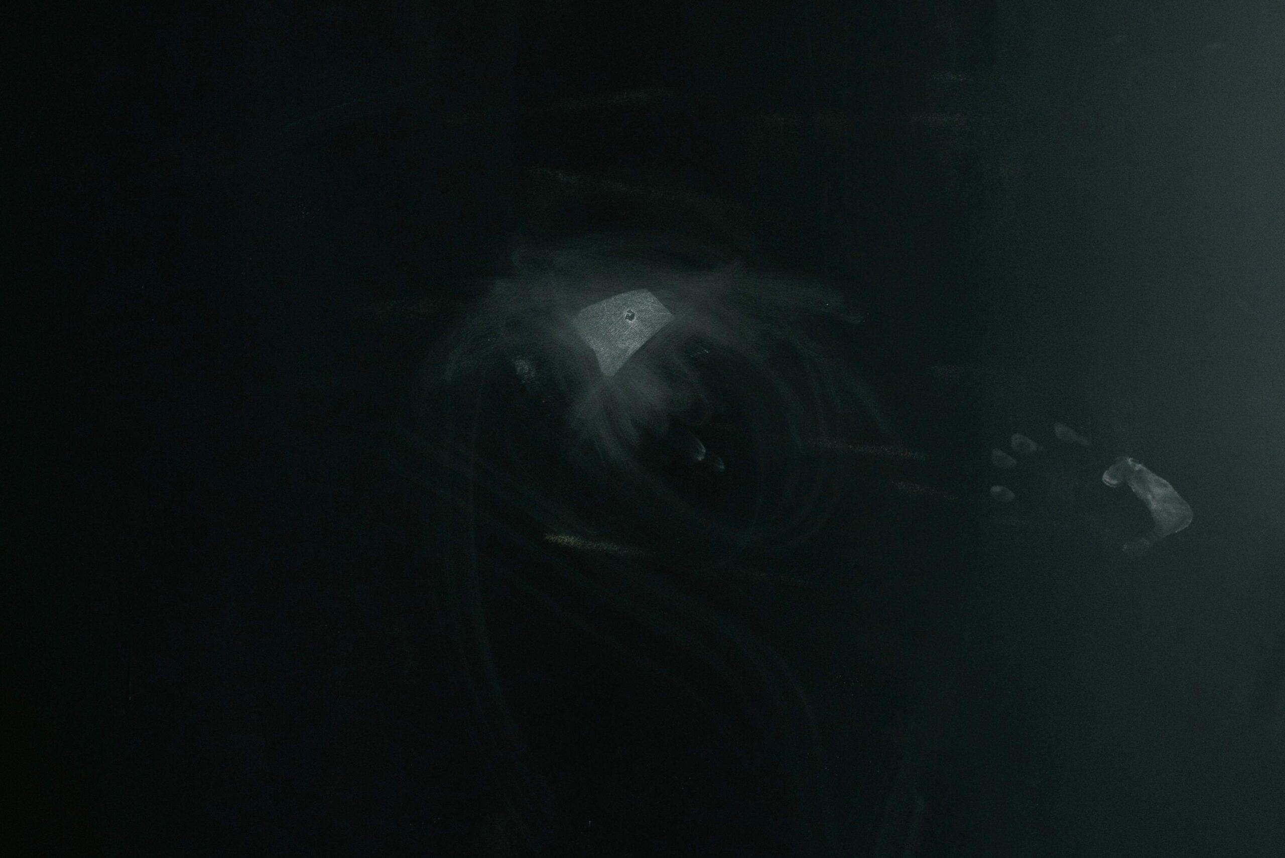 A dark abstract textured background featuring a subtle chalky effect on a black surface.